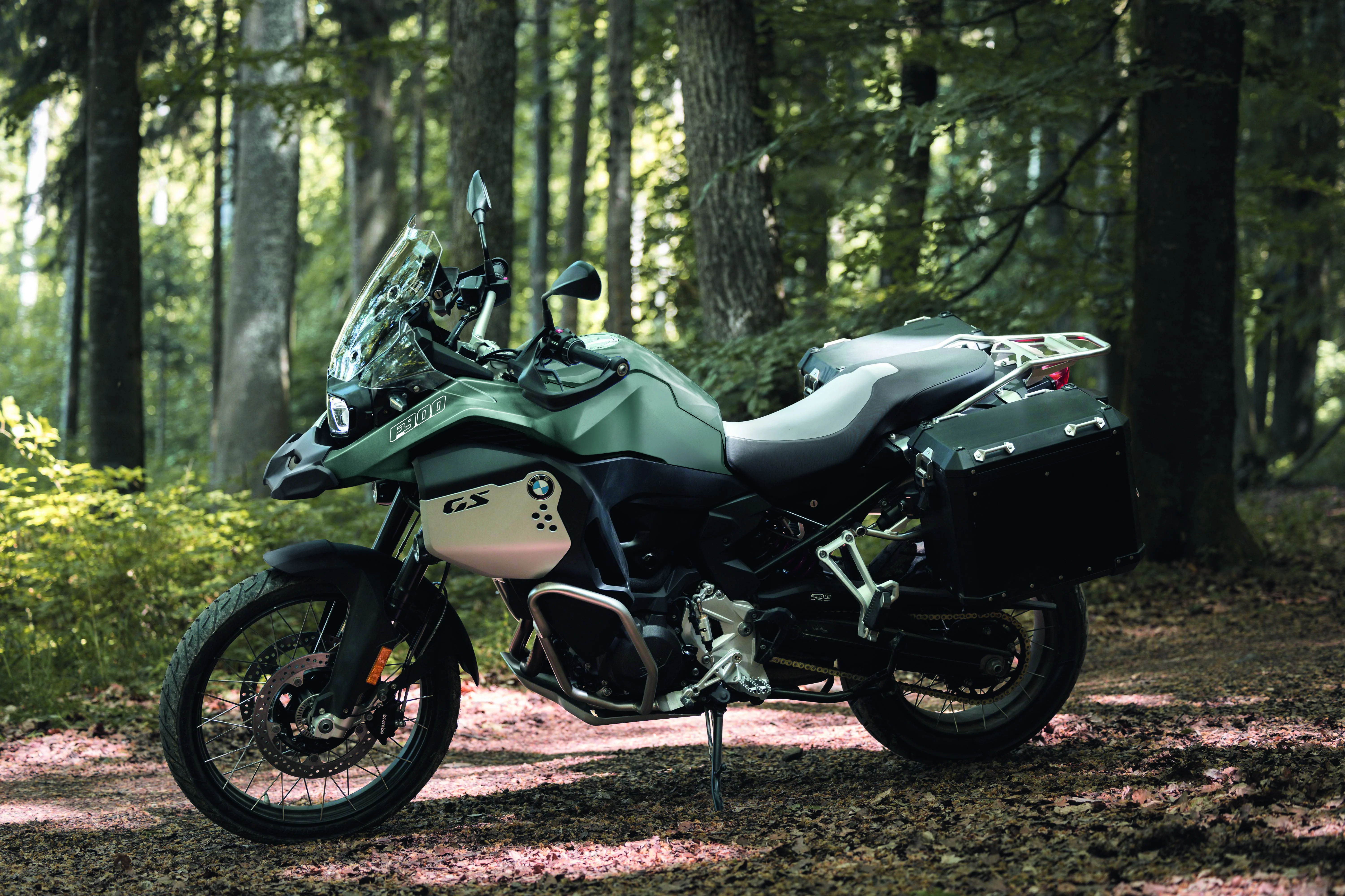 2026 BMW F 900 GS Adventure parked in a forest clearing with filtered daylight.