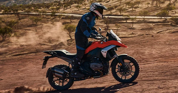BMW R 1300 GS riding through a dusty off-road landscape